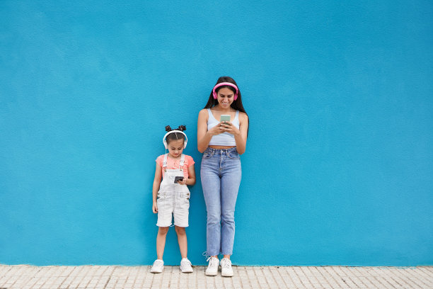 快乐的少女和小妹妹在智能手机上使用在线应用程序-年轻一代的女孩喜欢科技图片下载