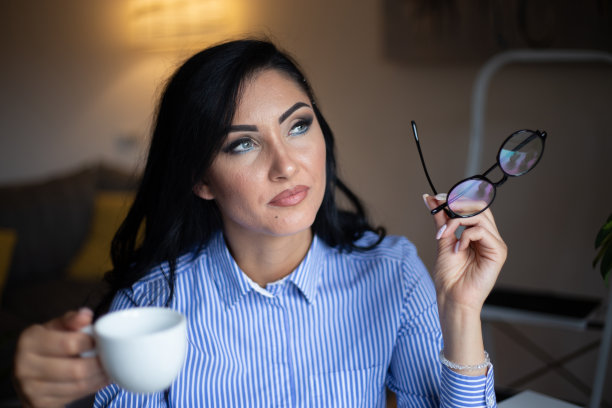 年轻女子享受她的咖啡，而工作或学习笔记本电脑在家庭办公室库存照片图片下载