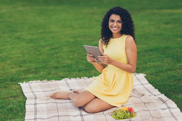 丰满的乐观的黑发女士照片坐在公园外坐着平板穿黄色衣服图片下载