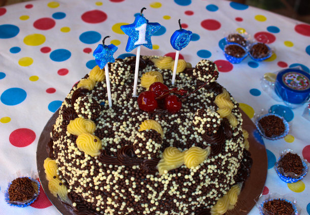 生日巧克力蛋糕和闪闪发光的星星蜡烛。宏观图景。蛋糕上有三个樱桃图片下载