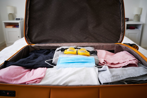 打开装有医用口罩和泳镜的手提箱。图片下载