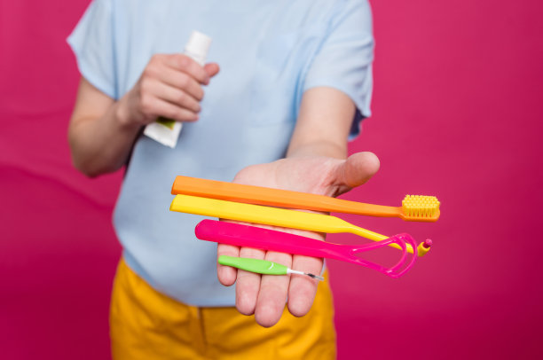 美丽的年轻女子使用一个口腔护理包，包括一个刮舌器，单簇和牙间刷图片下载