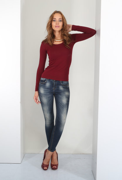 年轻美丽的女人在休闲穿着勃艮第针织衫和牛仔裤前面的白色背景。图片下载