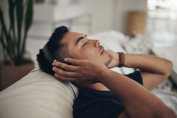 这是一个年轻人坐在沙发上听音乐的照片图片下载