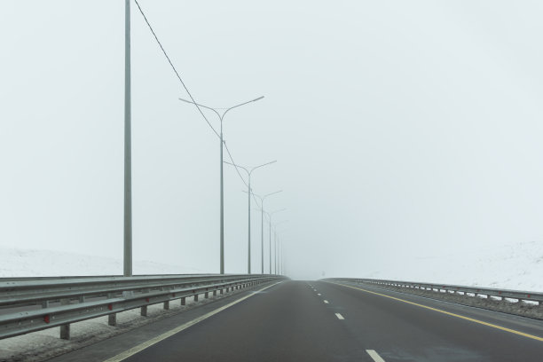 公路公路冬季。灰色，荒凉的风景，宽阔的公路上没有汽车。图片下载