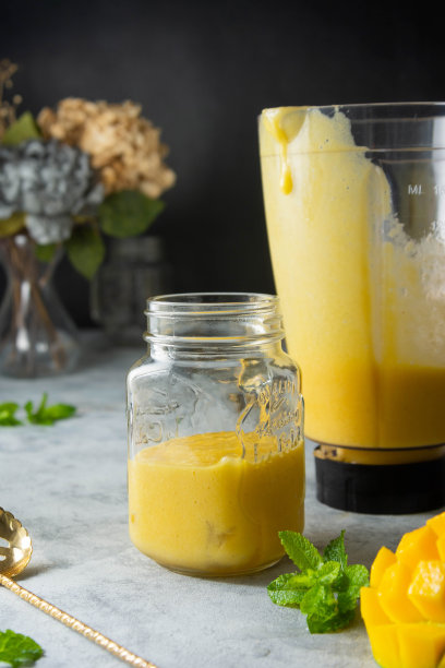 玻璃罐芒果冰沙，新鲜芒果和薄荷，深色背景图片下载