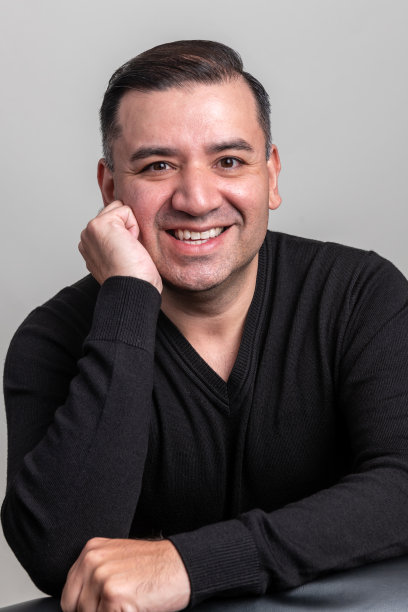 微笑的成熟男子看着灰色背景的相机图片下载