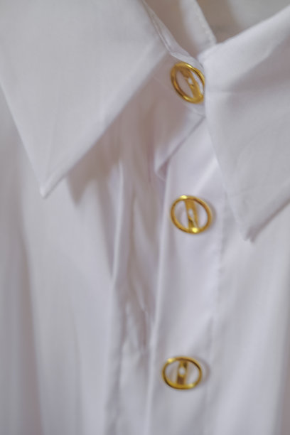 近距离散焦模糊白色衬衫与金色圆扣白领。女性和男性时尚。图片下载