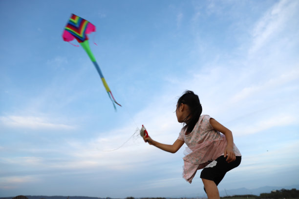 亚洲女孩在草地上玩和放风筝。图片下载