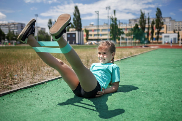 十多岁的女孩在城市的公共运动场用健身阻力带做运动图片下载