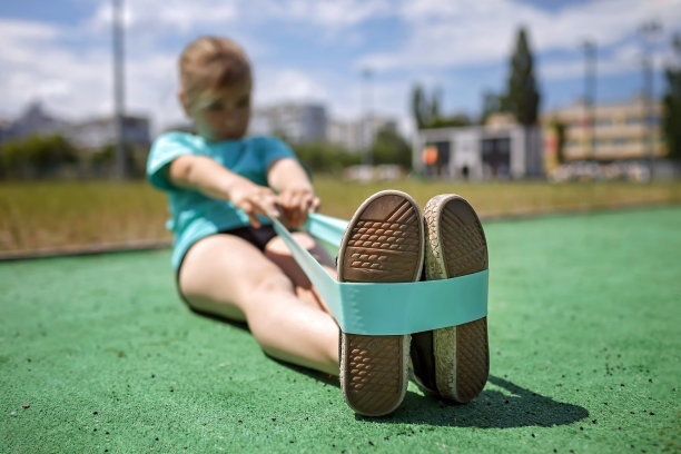 十多岁的女孩在城市的公共运动场用健身阻力带做运动图片下载