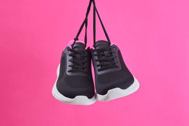 一双女性运动运动鞋跑步和健身用鞋带挂在粉红色的背景。时尚时尚的运动鞋。图片下载