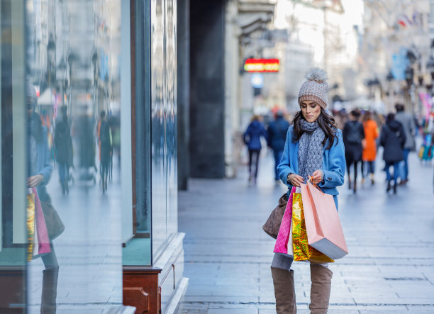 快乐女人是在城市的街道上度过一个购物日。图片下载