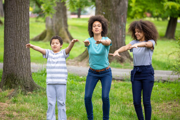 一名非洲裔美国妇女正在为与她的孩子们在公园慢跑热身。图片下载
