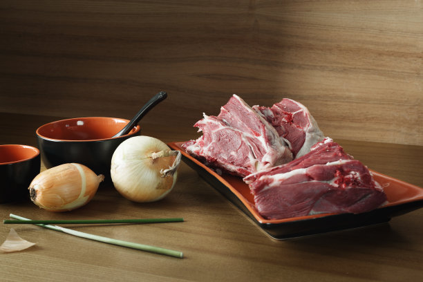 桌上的盘子里装着新鲜的生羊肉。黑暗的背景。图片下载