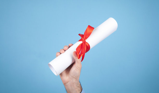 男手拿着带红丝带的文凭。图片下载