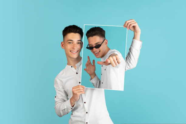 一个年轻的男孩，穿着白衬衫拿着他的肖像孤立在浅蓝色的背景。图片下载