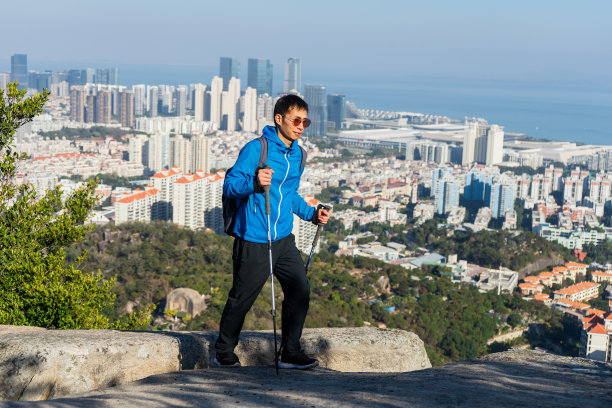 一名亚洲男子用登山杆向山顶走去图片下载