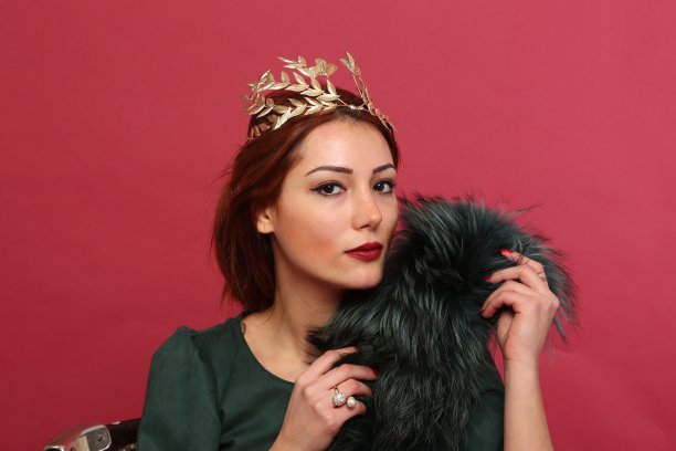 年轻漂亮的女人在红色的背景下穿着绿色的晚礼服。图片下载