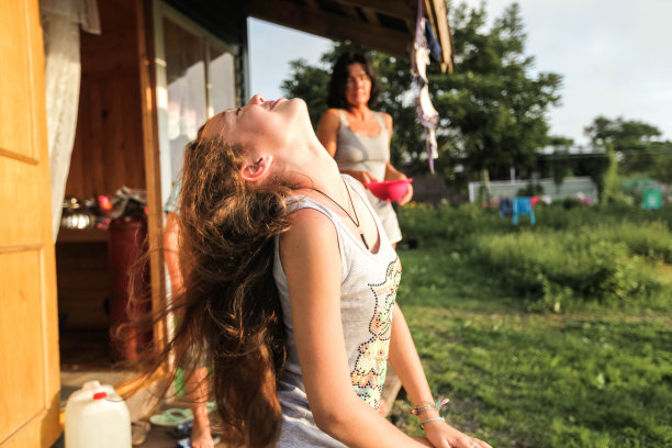 女孩在街上游泳后坐在房子附近擦干头发，妈妈看着她，在一起，生活方式，总体规划，自然，休息，旅行，幸福，童年，彩色照片，特写，股票照片图片下载