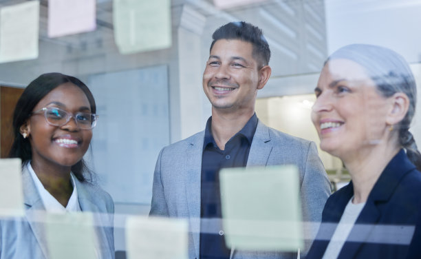 这张照片拍摄的是一群商人在办公室的玻璃墙上用笔记进行头脑风暴图片下载