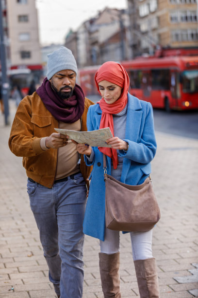 年轻的多种族夫妇在城市中漫步，使用地图探索景点图片下载