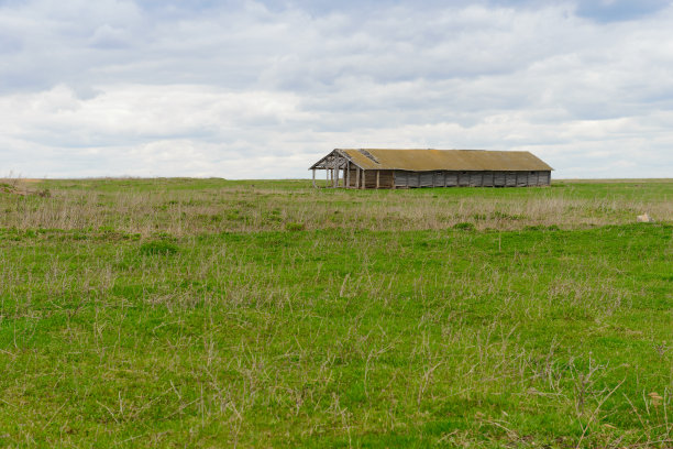 一个多云的春日，在一片空地上的一座废弃的旧建筑图片下载