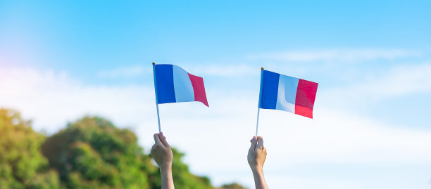 在蓝天背景下，手握法国国旗。法国国庆日，巴士底日和快乐的庆祝概念图片下载