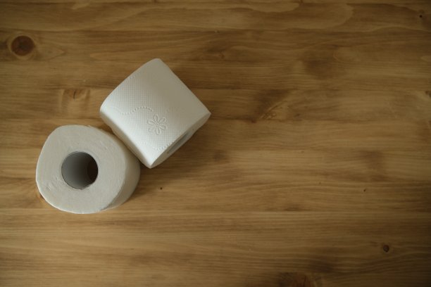 木桌上放着卫生纸。两个白色的卷。米色的颜色。俯视图图片下载