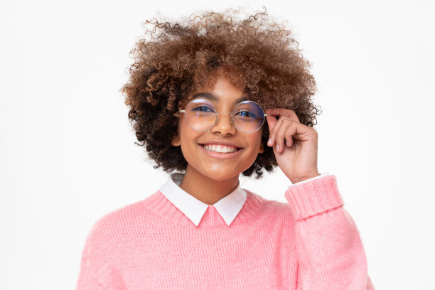 快乐微笑的非洲女学生拿着眼镜与一只手，孤立在灰色的背景图片下载