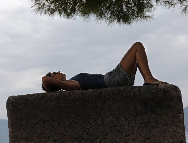 女性躺在石头上放松的剪影。图片下载