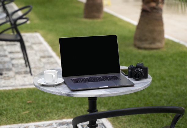 现代笔记本电脑和相机，还有一杯咖啡放在后院的桌子上图片下载