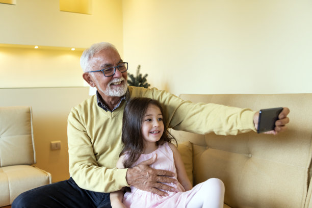 老爷爷和可爱小女孩在家自拍。永远不要停止制造回忆。图片下载