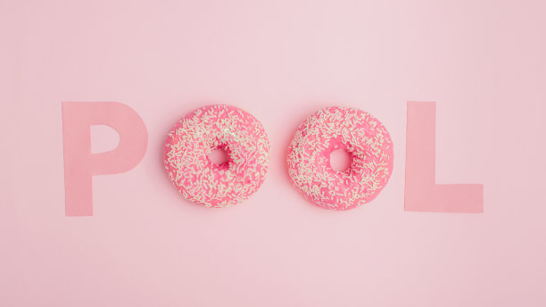 粉色甜甜圈和字母，游泳池和假期的创意夏季概念。极简的平面布局，粉彩背景。图片下载
