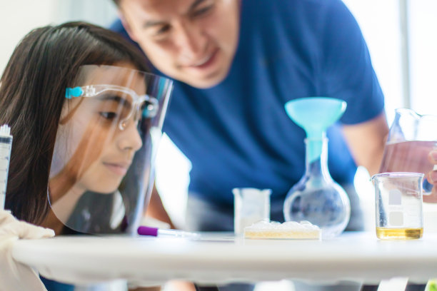 哥伦比亚裔千禧父亲与小学生女儿在家中进行科学实验（远程学习照片系列）图片下载