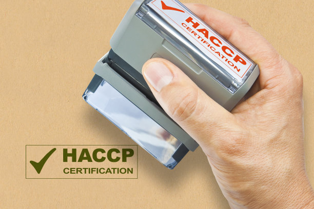手握印有HACCP认证(危害分析和关键控制点)的塑料印章-食品安全和食品行业的质量控制概念图像图片下载