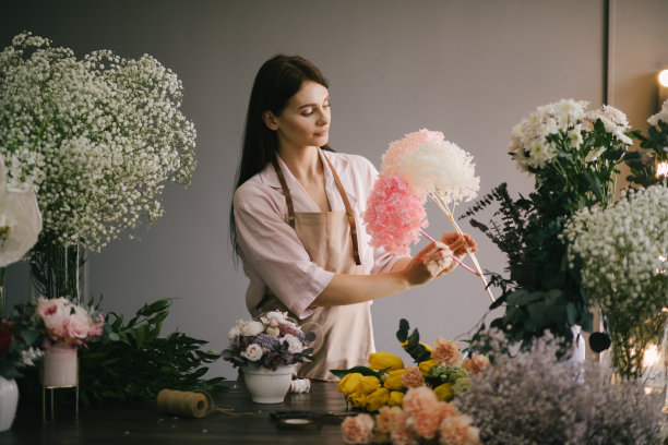年轻女子花匠在她的花室工作，用新鲜的植物和鲜花制作美丽的花束。图片下载