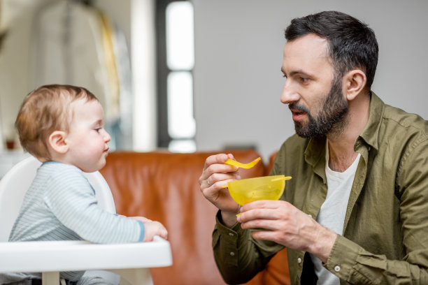 父亲用勺子喂一岁的小男孩。图片下载