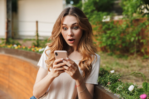 惊讶的年轻女孩在休闲服装使用手机图片下载