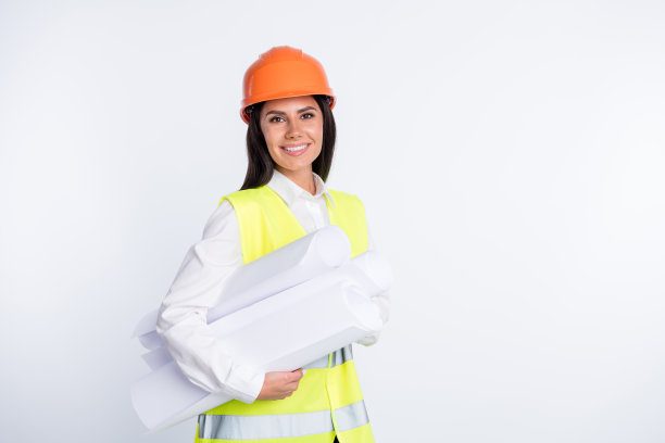 工程师女士的照片，手持多卷纸，牙齿微笑，戴头盔，衬衫，背心孤立的白色背景图片下载