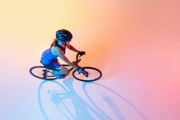 高角度的女自行车手骑自行车孤立的霓虹灯背景图片下载