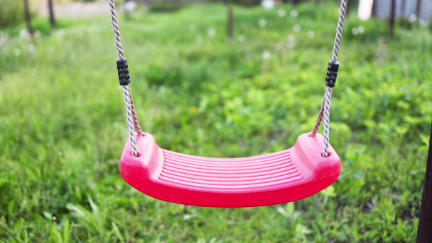 孤独的秋千悬挂在满是青草和树木的春天的花园里图片下载