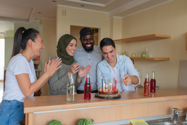快乐的多元民族朋友在现代公寓放松身心，享受生日派对图片下载