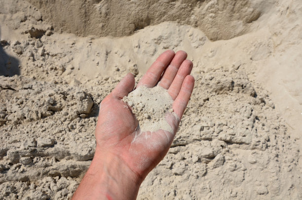 人手里拿着一种大小相同的石头、砂砾或鹅卵石的样品。大理石白色的碎石和灰棕色的碎石直接从采石场运来。图片下载