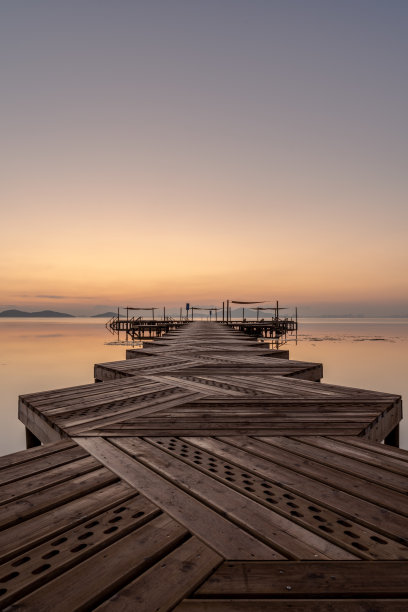 日出拍摄Mar Menor (Los Urrutias)，穆尔西亚，西班牙。日出的照片，一个曲折的木制码头或码头在黄金时间，通过平静的水域到达大海。图片下载
