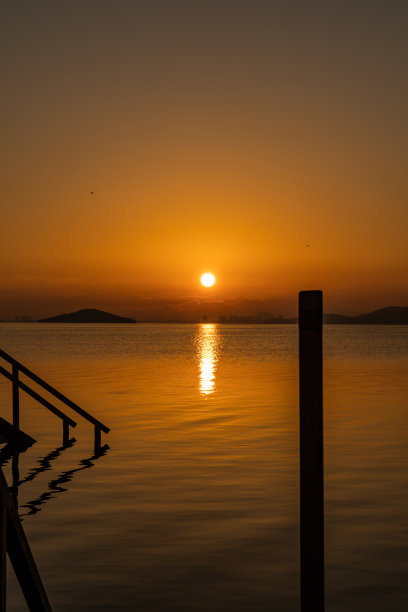 日出拍摄Mar Menor (Los Urrutias)，穆尔西亚，西班牙。日出的照片，一个码头到达大海通过平静的水域，与太阳反射的水。图片下载