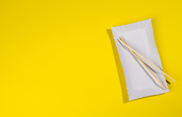 黄色背景的纸长方形盘子，木制筷子图片下载