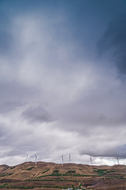 阴天下的草原上的风力发电机图片下载