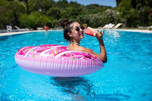 美丽迷人的女人喜欢在一个充气甜甜圈和西瓜池图片下载