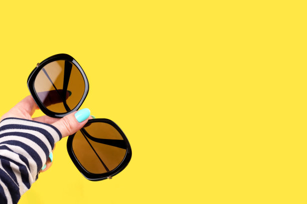 手与绿松石指甲与太阳镜在黄色的背景图片下载